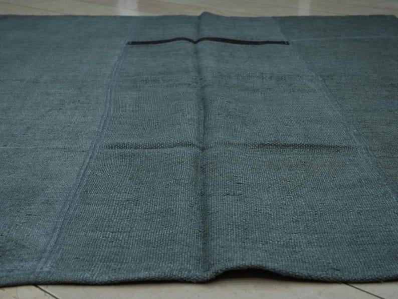 a close-up view of a dark green, textured rug or mat laid out on a wooden floor.