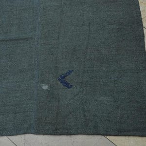 a close-up view of a dark-colored fabric, possibly a blanket or rug, placed on a tiled floor.