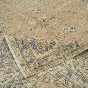a close-up view of a beige and blue patterned rug or carpet, with intricate floral and geometric designs.