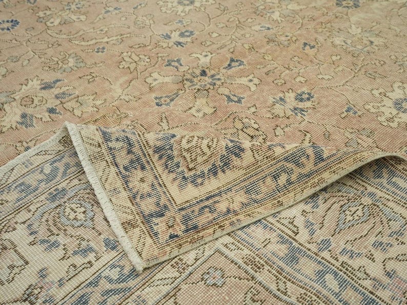 a close-up view of a beige and blue patterned rug or carpet, with intricate floral and geometric designs.