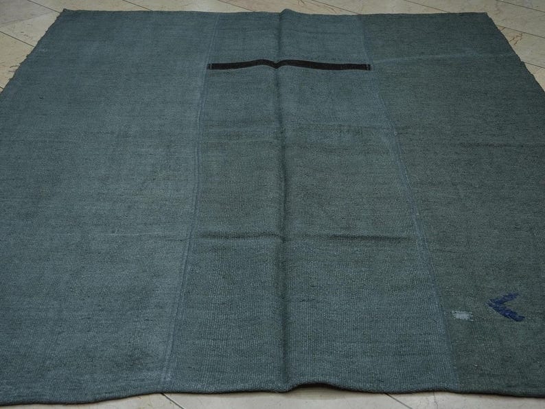 a large, square-shaped rug with a dark green color and a black stripe running through the center.