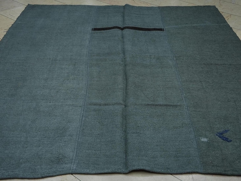 a large, square-shaped rug with a dark green color and a black stripe running through the center.