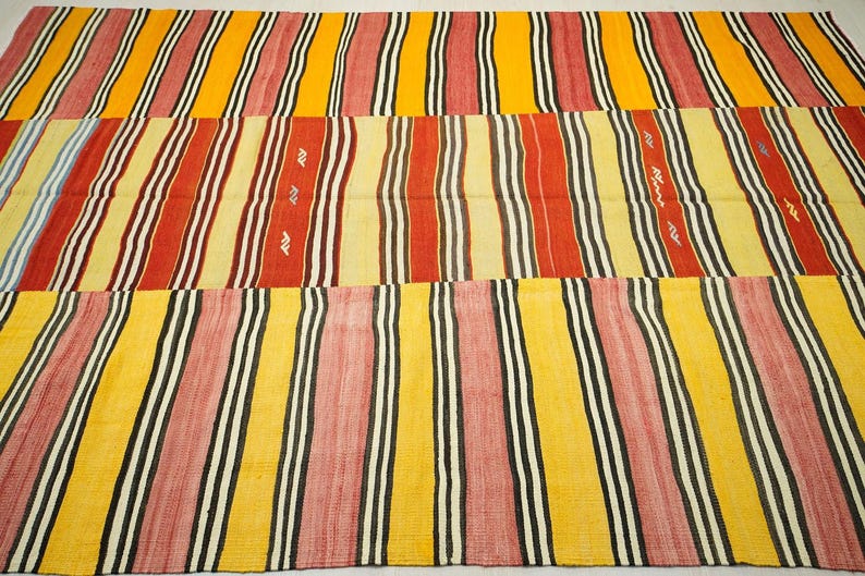 a vibrant, multi-colored rug with a repeating pattern of stripes in various colors, including red, yellow, and black.