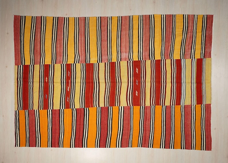 a vibrant, colorful textile with vertical stripes in various shades of red, yellow, and orange. The pattern is composed of multiple panels, creating a visually striking and intricate design.