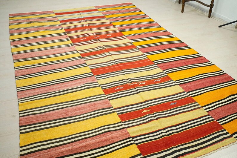 a large, colorful rug with a striped pattern in shades of red, yellow, and black.
