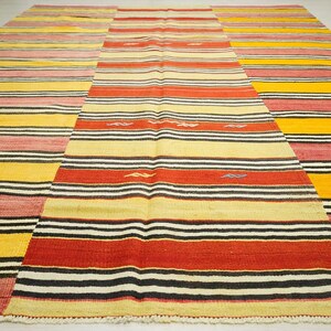 a large, colorful rug with a geometric pattern of stripes in various colors, including red, yellow, and black.