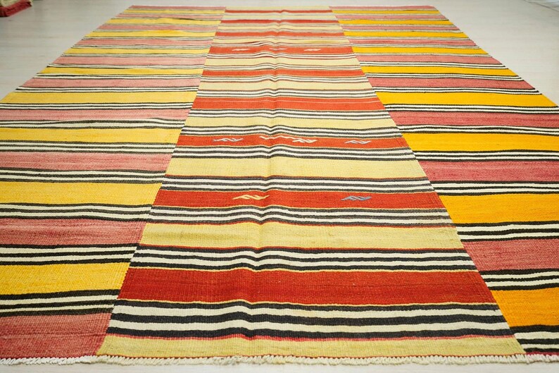 a large, colorful rug with a geometric pattern of stripes in various colors, including red, yellow, and black.