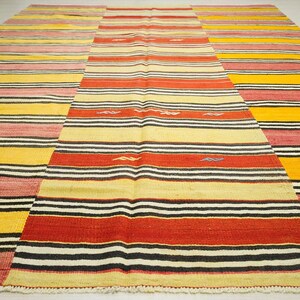 a large, colorful rug with a geometric pattern of stripes in various colors, including red, yellow, and black.