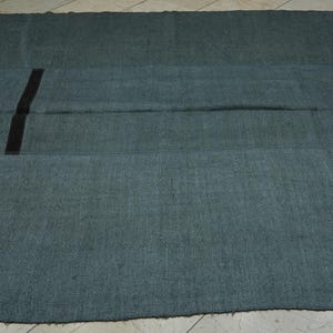a large, dark green rug with a black stripe running vertically down the center.