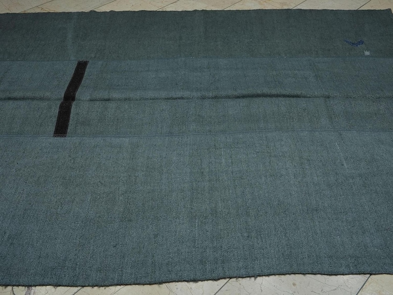 a large, dark green rug with a black stripe running vertically down the center.