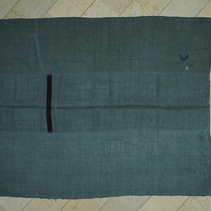 a large, rectangular green cloth or blanket laid out on a tiled floor.