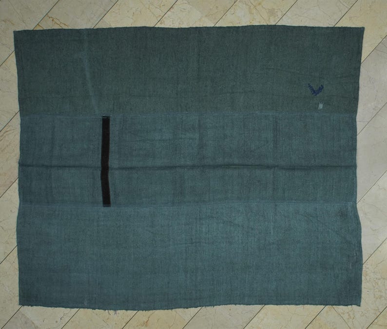a large, rectangular green cloth or blanket laid out on a tiled floor.