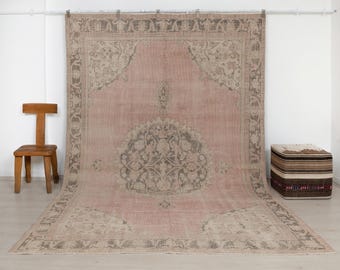May include: A large rectangular area rug featuring a dusty pink field with a central medallion and intricate floral border patterns in muted grey and beige tones. The rug displays a symmetrical design with corner motifs and a detailed central floral element.
