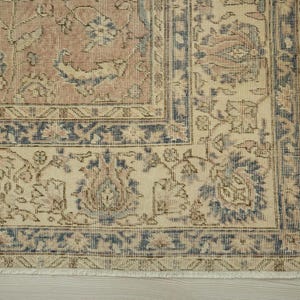 a close-up view of a decorative rug with intricate floral patterns in shades of beige and blue.