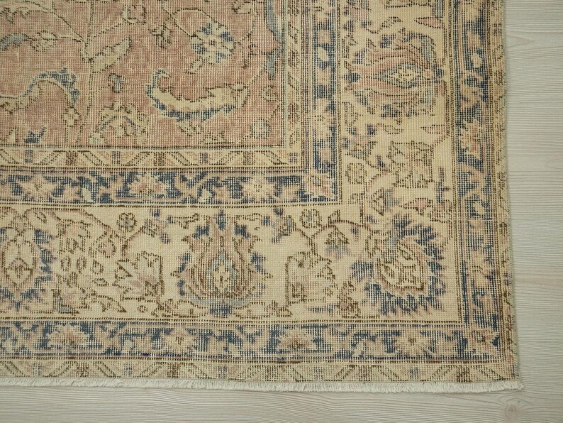 a close-up view of a decorative rug with intricate floral patterns in shades of beige and blue.