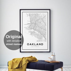 May include: Black and white map print of Oakland, California with the city name and state printed at the bottom of the map. The map is framed in a black frame and hanging on a white wall.