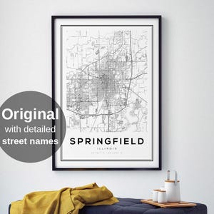 Puede incluir: Un mapa en blanco y negro enmarcado de Springfield, Illinois, con nombres de calles detallados. El mapa cuelga sobre un banco azul marino acolchado con una manta amarilla y una bandeja de madera con artículos de cerámica blanca.