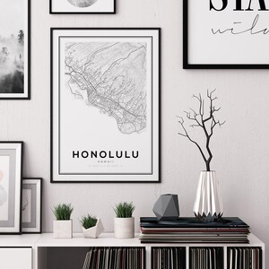 K&ouml;nnte beinhalten: Ein Schwarzwei&szlig;-Kartenabdruck von Honolulu, Hawaii, mit dem Stadtnamen und den Koordinaten unter der Karte. Der Druck ist in einem schwarzen Rahmen gerahmt und h&auml;ngt an einer wei&szlig;en Wand. Unter dem Druck befinden sich Pflanzen und eine Vase mit Zweigen auf einem wei&szlig;en Regal.