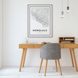 K&ouml;nnte beinhalten: Ein heller Holzschreibtisch mit zwei Schubladen und einem grauen Stoffstuhl. An der Wand &uuml;ber dem Schreibtisch h&auml;ngt eine gerahmte Karte von Honolulu, Hawaii. Von der Decke h&auml;ngen drei Gl&uuml;hbirnen.