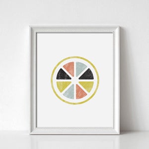May include: Framed art print featuring a colorful, geometric design of a citrus fruit slice. The artwork includes segments in coral, light blue, yellow, and black, set against a white background. The print is enclosed in a white frame.