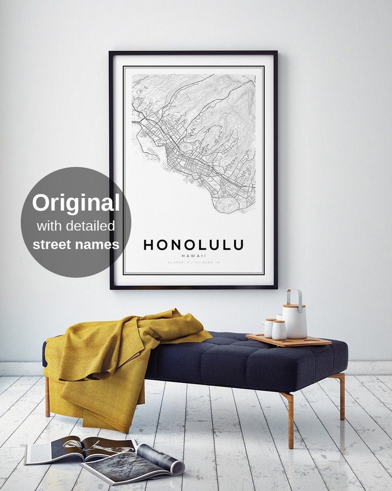 K&ouml;nnte beinhalten: Ein schwarzer gerahmter Druck einer detaillierten Karte von Honolulu, Hawaii. Die Karte zeigt Stra&szlig;ennamen und Sehensw&uuml;rdigkeiten. Der Druck h&auml;ngt an einer wei&szlig;en Wand &uuml;ber einer dunkelblauen Bank mit einer gelben Wolldecke.