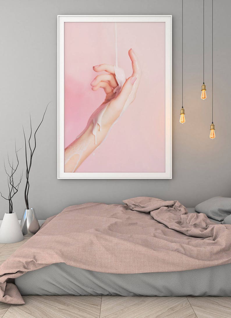 Pu&ograve; includere: Una stampa artistica incorniciata raffigurante una mano con una sostanza bianca che vi si versa sopra, su uno sfondo rosa. L'opera d'arte &egrave; esposta sopra un letto con un copriletto rosa e lenzuola grigie. Sono visibili lampadine a sospensione.