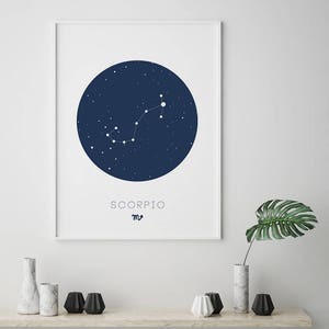 Puede incluir: Una impresi&oacute;n enmarcada en blanco con un c&iacute;rculo azul que representa la constelaci&oacute;n de Escorpio. El texto "SCORPIO" y el s&iacute;mbolo astrol&oacute;gico de Escorpio est&aacute;n impresos debajo del c&iacute;rculo.