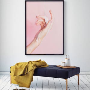 Pu&ograve; includere: Una stampa incorniciata raffigurante una mano con un liquido versato sopra su uno sfondo rosa. Sotto, una panca blu navy trapuntata con una coperta gialla e un vassoio di legno con una teiera e tazze. Ci sono riviste sul pavimento.