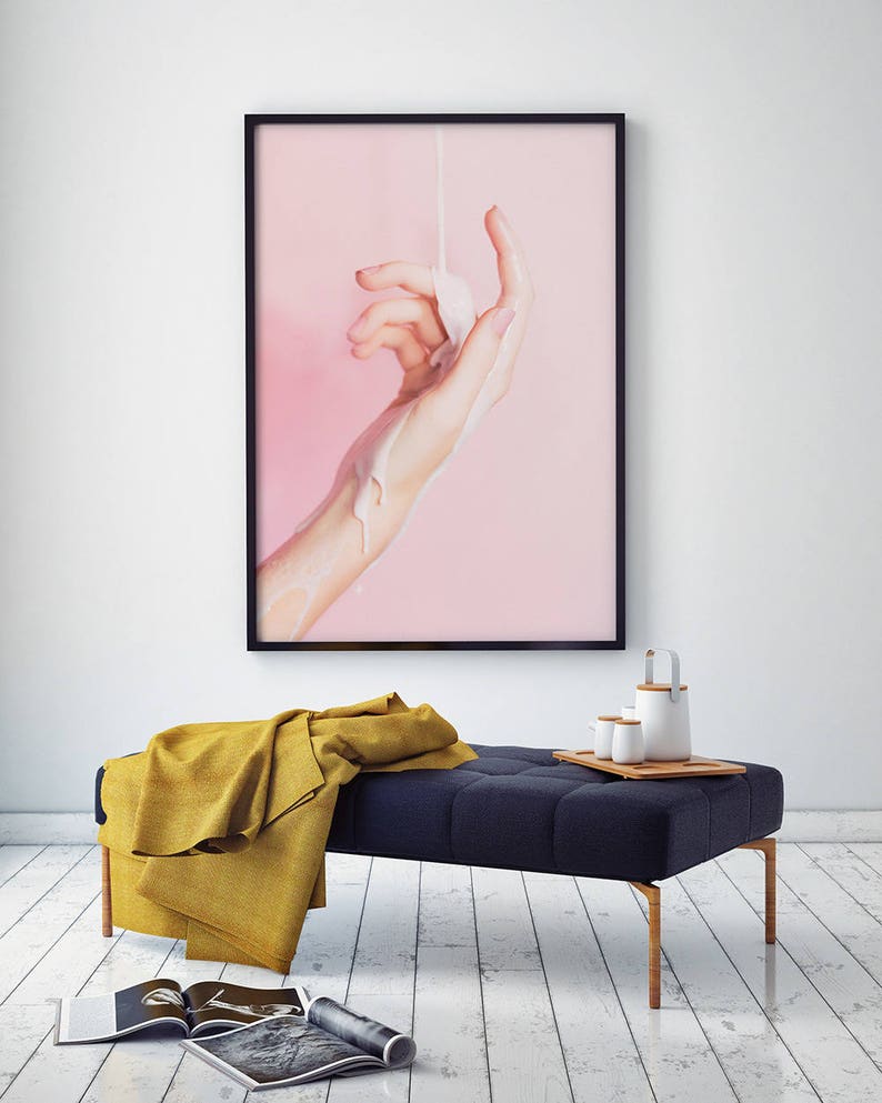 Pu&ograve; includere: Una stampa incorniciata raffigurante una mano con un liquido versato sopra su uno sfondo rosa. Sotto, una panca blu navy trapuntata con una coperta gialla e un vassoio di legno con una teiera e tazze. Ci sono riviste sul pavimento.