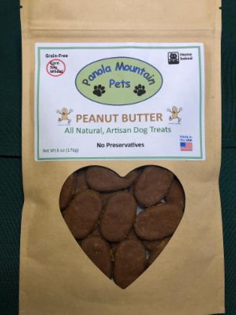 May include: A brown paper bag with a heart-shaped window showing peanut butter dog treats. The bag has a label that says "Panola Mountain Pets" and "Peanut Butter All Natural, Artisan Dog Treats".