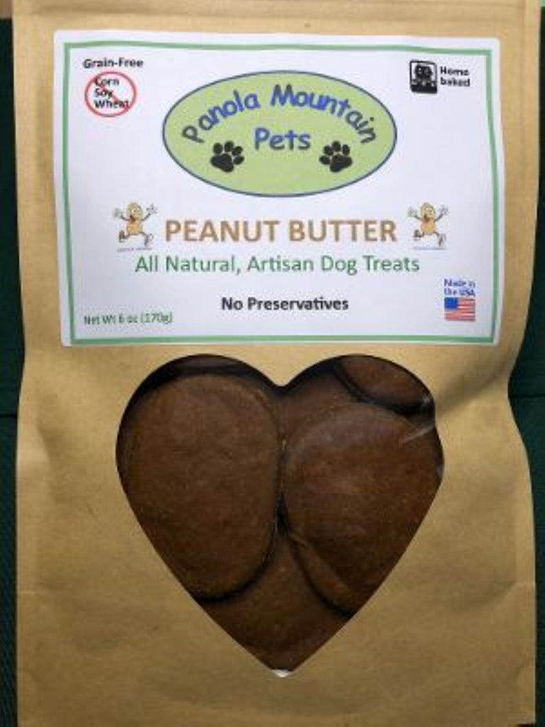 May include: A brown paper bag with a heart-shaped window showing peanut butter dog treats. The bag has a label that says "Panola Mountain Pets" and "Peanut Butter" with the text "All Natural, Artisan Dog Treats, No Preservatives".
