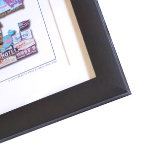 May include: A framed artwork featuring a collage of vintage signs and text. The signs are in various colors and styles, with some featuring text like "Hotel West" and "Lounge Wes-1966". The artwork is framed in a black frame.