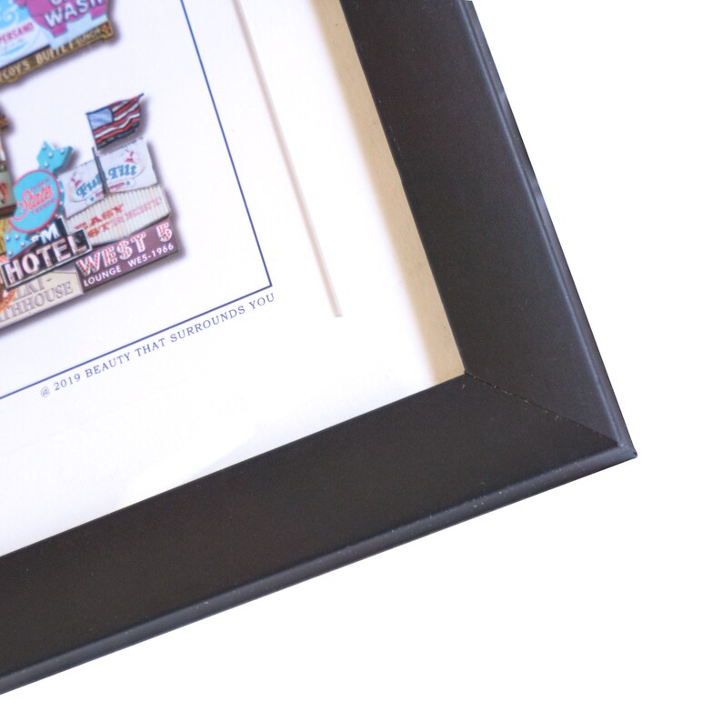 May include: A framed artwork featuring a collage of vintage signs and text. The signs are in various colors and styles, with some featuring text like "Hotel West" and "Lounge Wes-1966". The artwork is framed in a black frame.