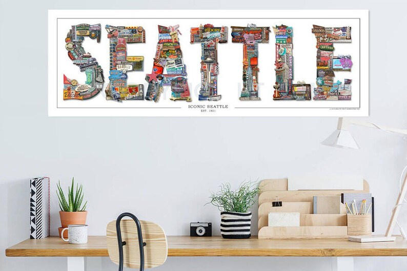 May include: A white poster with the word "SEATTLE" spelled out in large letters. Each letter is made up of smaller images of iconic Seattle landmarks, businesses, and attractions. The text "ICONIC SEATTLE EST. 1851" is printed below the word "SEATTLE".