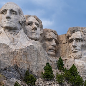 Puede incluir: Una vista cercana del Monumento Nacional Monte Rushmore, que presenta las caras talladas de cuatro presidentes estadounidenses: George Washington, Thomas Jefferson, Theodore Roosevelt y Abraham Lincoln. El monumento está tallado en una pared de roca de granito y es un destino turístico popular.