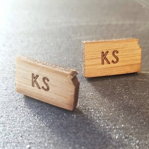 May include: Two wooden state-shaped ornaments with the initials "KS" engraved on them. The ornaments are light brown and have a natural wood grain.