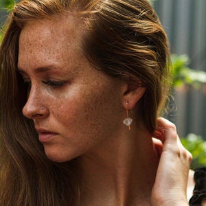 May include: A woman with freckles and long, red hair wearing a delicate gold chain with a small white stone pendant.