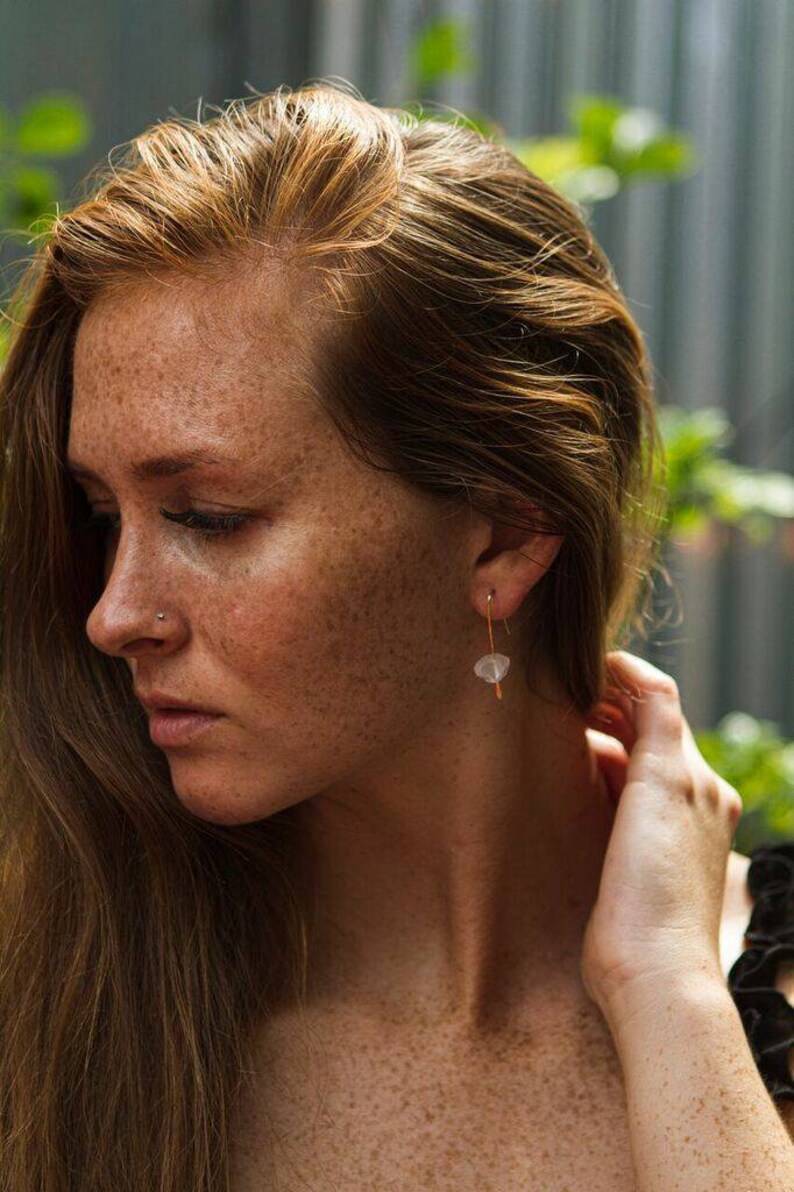 May include: A woman with freckles and long, red hair wearing a delicate gold chain with a small white stone pendant.