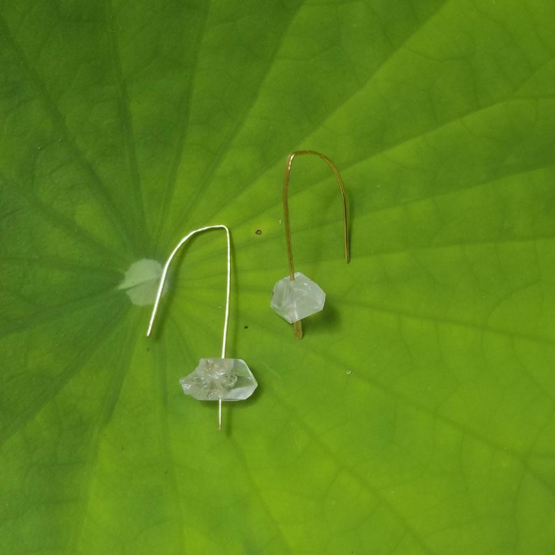 May include: A pair of delicate earrings with clear crystal stones hanging from gold wire.