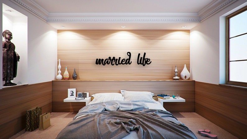 K&ouml;nnte beinhalten: Ein Schlafzimmer mit einer Holzwand und einem Bett mit einer grauen Decke. An der Wand steht in schwarzen Buchstaben "married life" geschrieben.