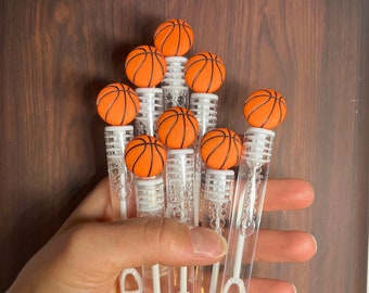 Puede incluir: Un grupo de varitas de burbujas de plástico transparente con tapas en forma de baloncesto naranja y negro.