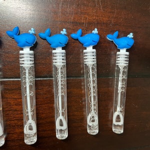 May include: Four blue whale bubble wands with clear plastic tubes and white bubble wands.