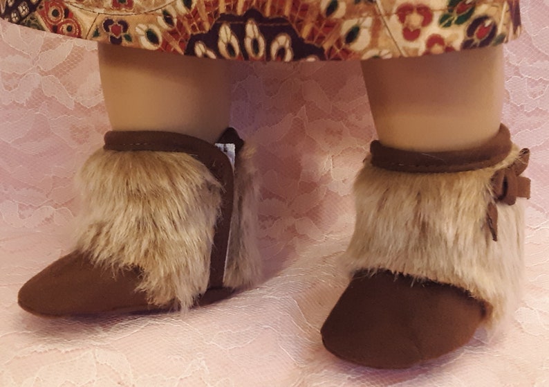 May include: A pair of brown suede boots with faux fur trim. The boots have a pointed toe and a low heel.