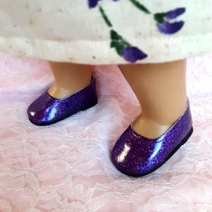 May include: A pair of purple glitter shoes with a rounded toe and a low heel.