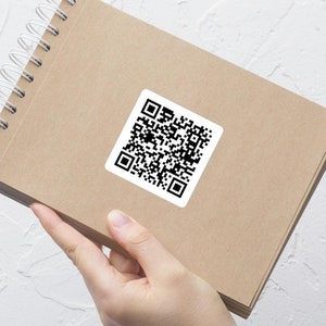 May include: A brown notebook with a spiral binding and a black and white QR code sticker on the front cover.