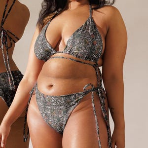 May include: Two women wearing a black and brown floral print bikini top and bottom. The bikini top is a triangle style with adjustable straps. The bikini bottom is a high-cut style with ties on the sides.