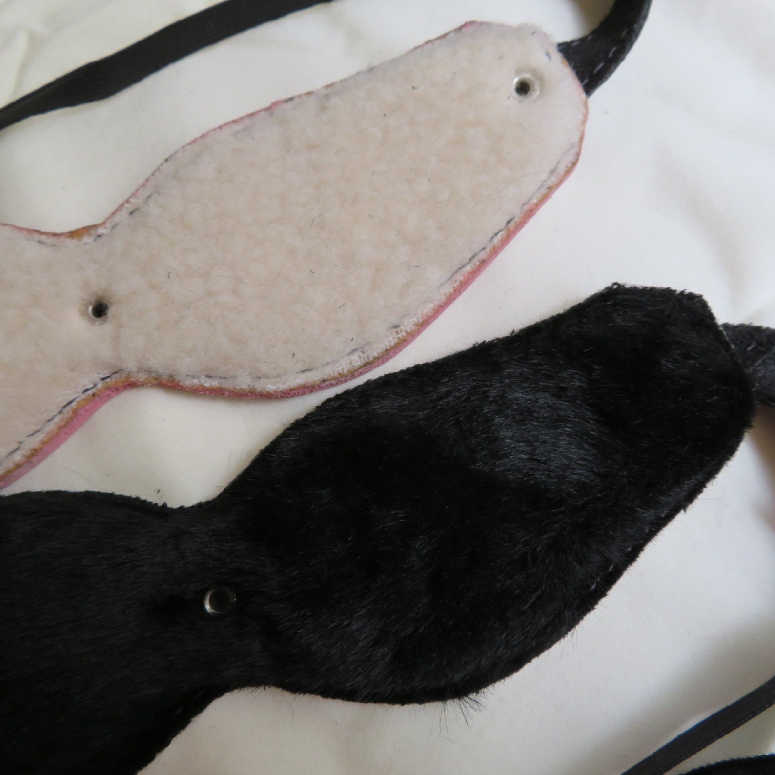 Closeup of black and white fur-lined leather Cat’s Eyes blindfolds, perfect for BDSM restraint play