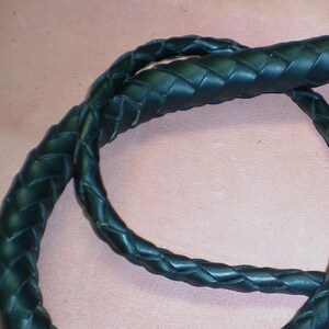 May include: Close-up of a black leather braided whip. The whip is coiled and the braided texture is visible.