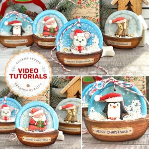 Puede incluir: Cuatro adornos navideños decorados en forma de bolas de nieve. Cada adorno presenta un personaje diferente: Papá Noel, un pingüino, un ratón y un zorro. Los adornos están decorados con glaseado blanco para parecer nieve y tienen una base de madera marrón con las palabras "Feliz Navidad" escritas en ellos.