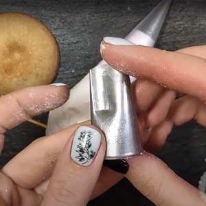 May include: A silver metal piping tip with a star-shaped opening. The tip is labeled "17" and "K REAL".